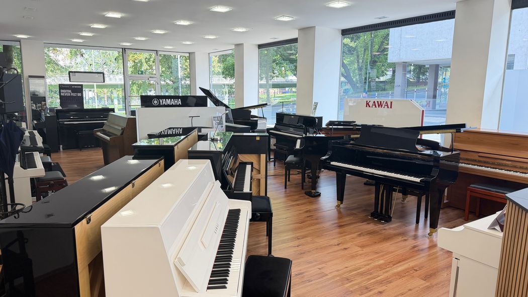 Moderne Klavierausstellung mit verschiedenen Instrumenten in hellem Showroom.