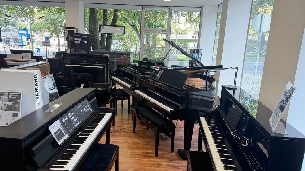 Moderne Musikwerkstatt mit mehreren Klavieren, Synthesizern und Studioausrüstung vor großen Fenstern.