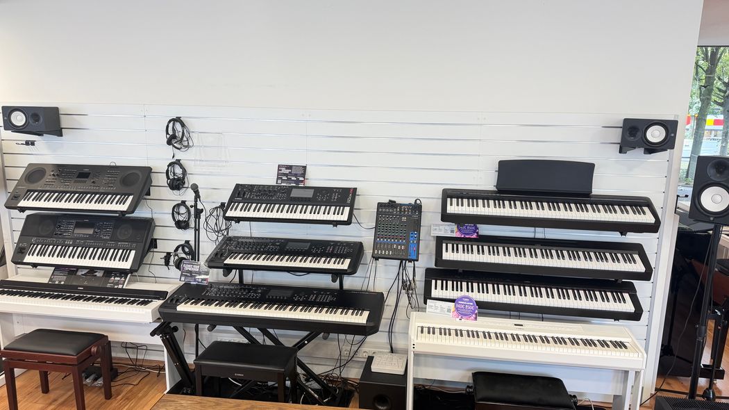 Vier Keyboards und Synthesizer in Studioaufstellung mit Pflanzen-Deko und weißer Wand.