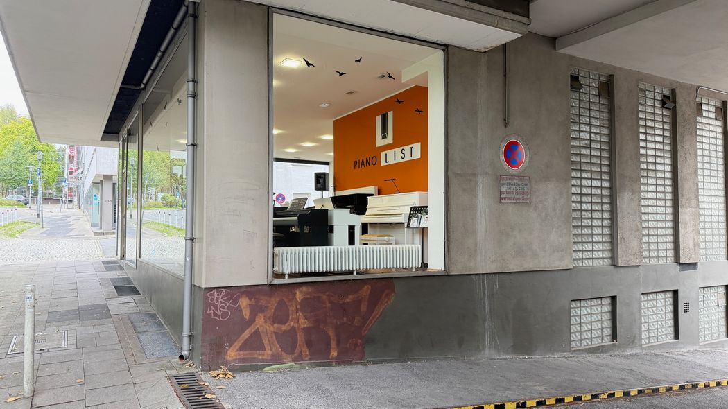 Bauarbeitsstelle vor einem neu gestalteten Ladenlokal mit orangefarbenem Innenausbau.